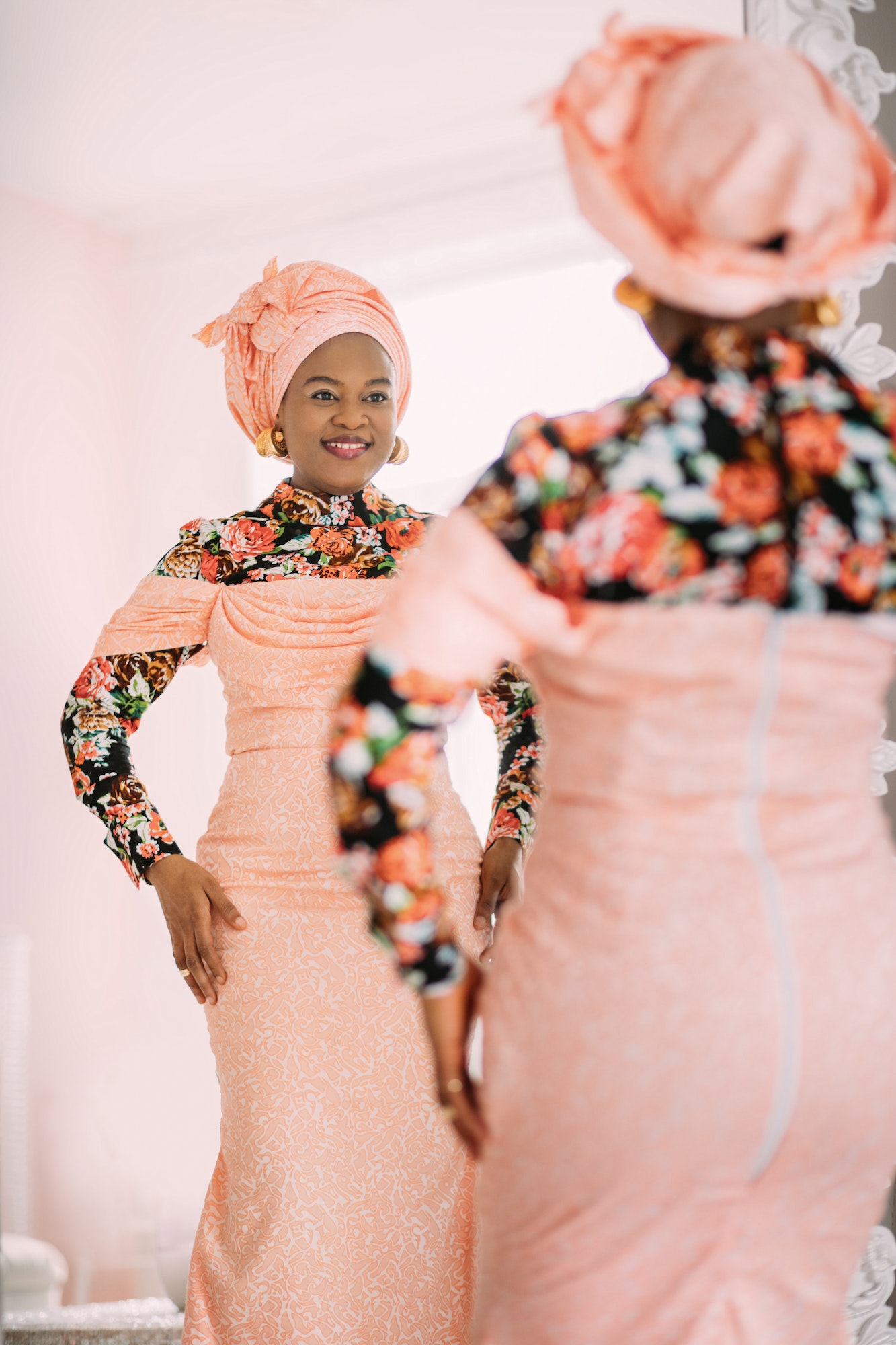 Studio shot of joyful pretty African lady wearing stylish pink dress with traditional print and